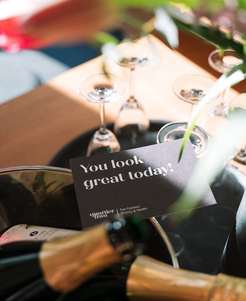 Eine Nahaufnahme von Champagner und Gläsern mit einem schwarzen Schild: "You look great today!"