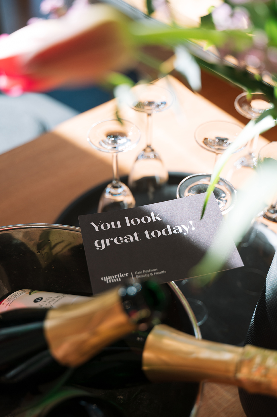 Eine Nahaufnahme von Champagner und Gläsern mit einem schwarzen Schild: "You look great today!"