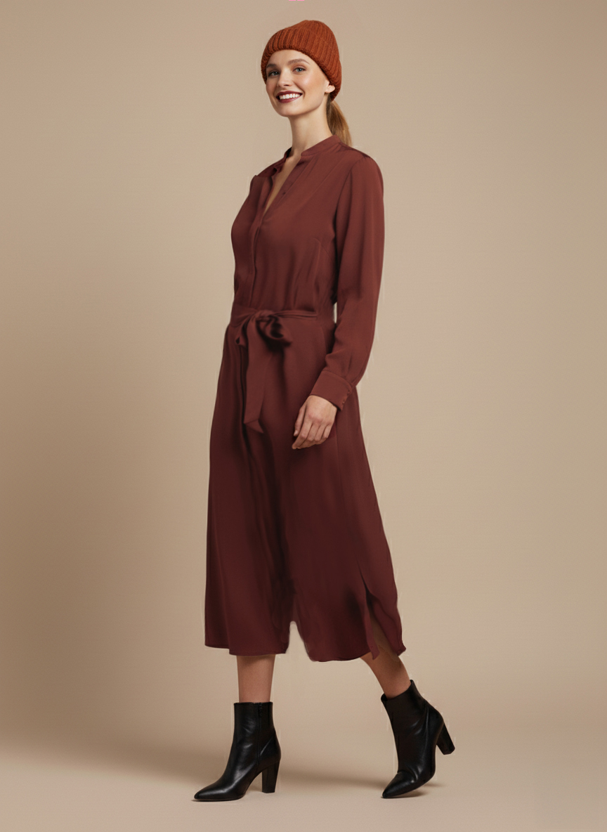Eine lächelnde Person trägt ein kastanienbraunes Kleid und schwarze Stiefeletten.